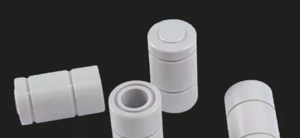Weiße zylindrische modulare Rohrverbinder auf schwarzem Hintergrund.