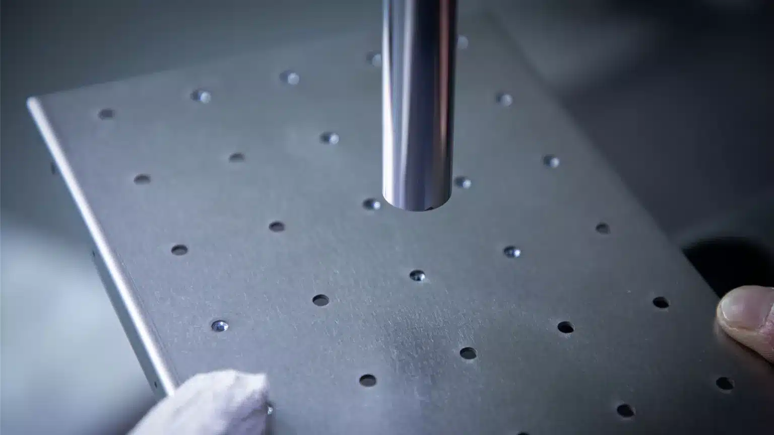 Metal plate with holes and cylindrical tool nearby.