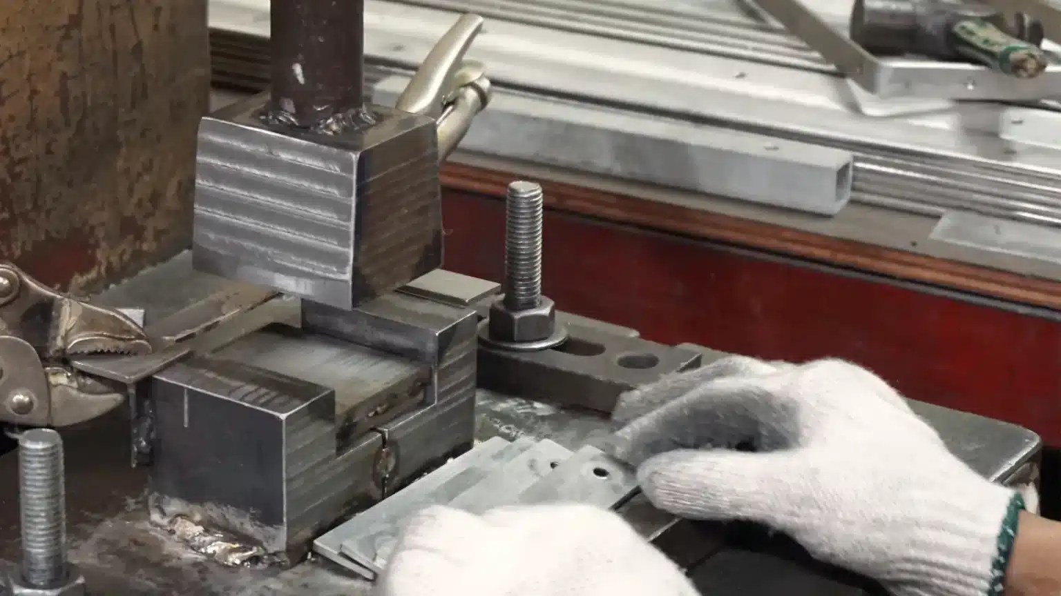 Metalworking equipment with gloved hands adjusting it.