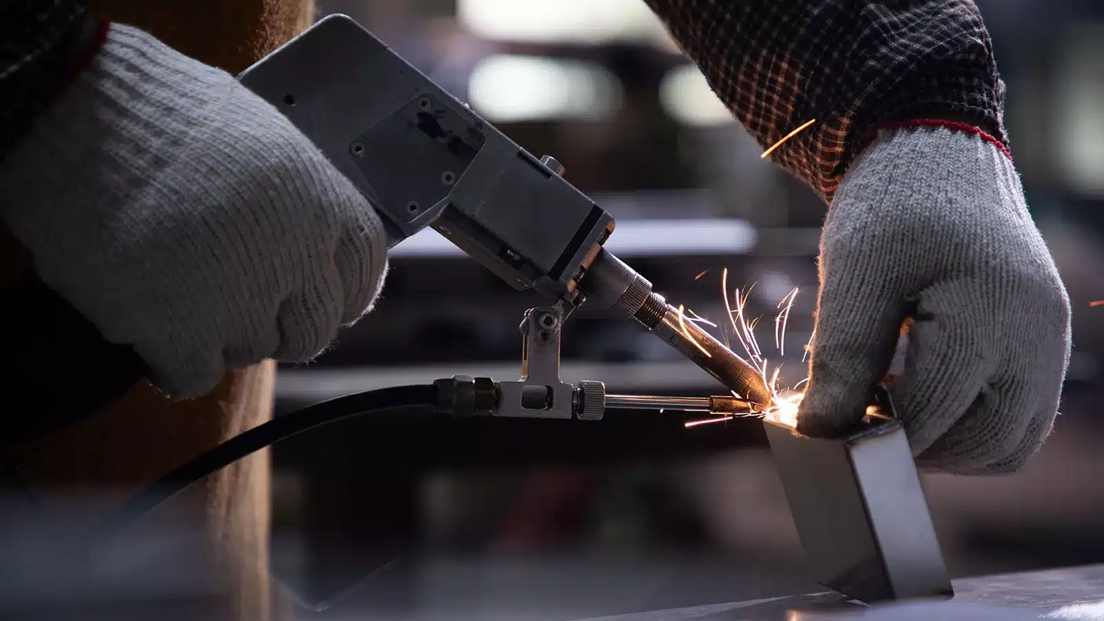 Person welding metal piece, sparks flying.